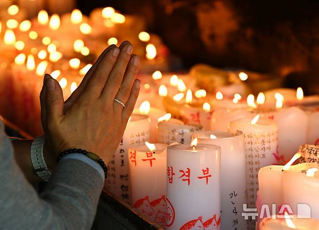 [화성=뉴시스] 김종택 기자 = 2026학년도 대학수학능력시험(11월13일)을 한달 앞둔 13일 경기 화성시 용주사에서 수험생 학부모가 자녀의 수능 고득점을 기원하며 촛불 앞에서 기도하고 있다. 2025.10.13. jtk@newsis.com