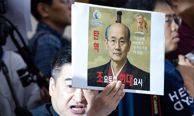 최혁진 무소속 의원이 13일 서울 여의도 국회에서 열린 법제사법위원회의 대법원 등에 대한 국정감사에서 조희대 대법원장에게 질의하며 손팻말을 들어보이고 있다. 뉴스1