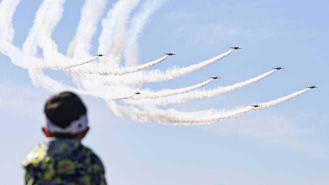 A child watches an aerobatic performance by the Air Force’s Black Eagles at the 2023 Seoul International Aerospace and Defense Exhibition (ADEX) at Seoul Air Base in Seongnam, Gyeonggi, Oct. 22, 2023. [YONHAP]