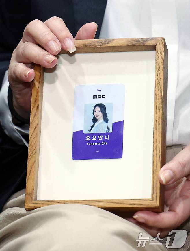 직장 내 괴롭힘을 호소하며 스스로 목숨을 끊은 MBC 기상캐스터 오요안나 씨의 어머니 장연미 씨가 15일 오전 서울시 마포구 상암동 MBC 상암사옥 골든마우스홀에서 열린 MBC-고 오요안나 유족 기자회견에서 고인의 명예 사원증을 들어 보이고 있다. 2025.10.15/뉴스1 ⓒ News1 박정호 기자