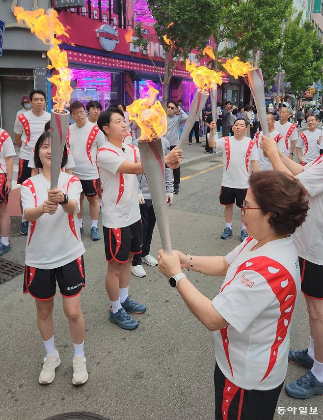 13일 부산 연제구 연산교차로 인근 도로에서 제106회 전국체육대회 성화 봉송 주자들이 앞선 구간을 달려온 주자들에게 불꽃을 넘겨받고 있다. 김화영 기자 run@donga.com