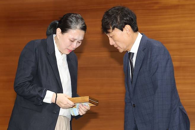 안형준 MBC 사장(오른쪽)이 15일 서울 마포구 MBC 사옥에서 열린 기자회견에서 직장 내 괴롭힘을 호소하며 숨진 기상캐스터 오요안나씨 어머니 장연미씨에게 고인의 명예사원증을 전달한 뒤 고개를 숙이고 있다. 연합뉴스