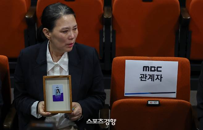 직장 내 괴롭힘을 호소하며 숨진 MBC 기상캐스터 고 오요안나 씨 어머니 장연미 씨가 15일 서울 마포구 상암동 MBC 사옥에서 열린 기자회견에서 고인의 명예사원증을 받은 뒤 눈물을 흘리고 있다. 성동훈 기자