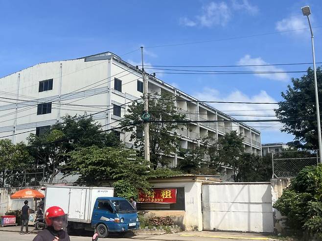 한 노점상이 16일 캄보디아 수도 프놈펜 외곽 센속에 위치한 원구단지에서 차와 다과를 판매하고 있다. 원구단지 정문에는 '부동산 임대'라는 현수막이 중국어로 붙어 있다. 사진=김준석 특파원