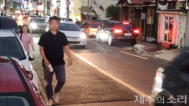 주차된 차량을 피해 차도를 걷는 사람들과 중앙선은 넘어 주행 중인 차량들. ⓒ제주의소리