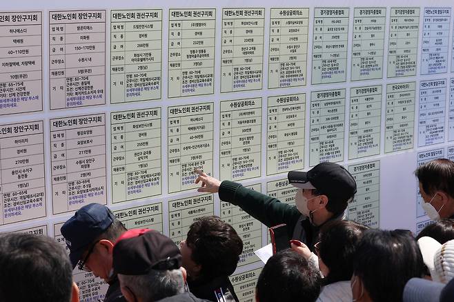 Job seekers aged 60 and older look at a job posting board during the 17th Senior Job Fair held at Hwaseong Haenggung Square in Paldal District, Suwon, Gyeonggi, on March 28. [NEWS1]