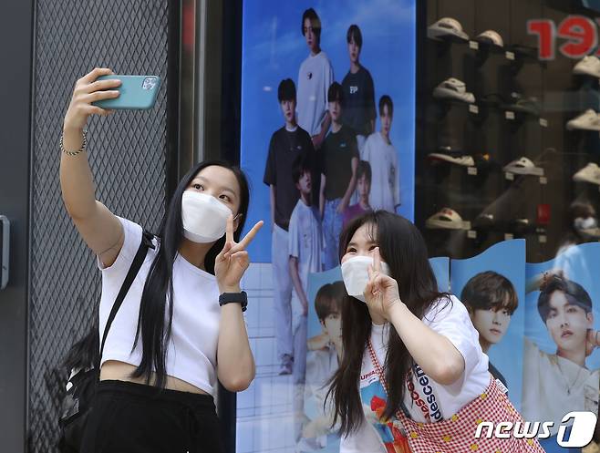 서울 중구 명동 한 매장에 걸려있는 BTS의 광고 사진 앞에서 해외 팬들이 기념 촬영을 하고 있다.. 2021.5.24/뉴스1 ⓒ News1 권현진 기자