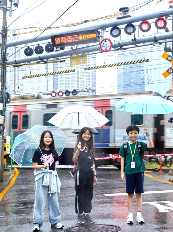 한강백년다리길을 탐방한 황지유·윤보영·최수혁(왼쪽부터) 학생기자가 백빈 건널목 주변 땡땡 거리에서 지나가는 기차를 배경으로 사진을 찍었다.