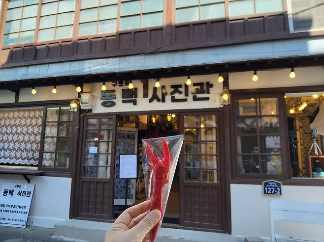 구룡포 일본인 가옥거리에 자리한 ‘동백사진관’ 앞에서 추억을 담은 집게 모양 빨간 볼펜 기념품을 들고 기념사진을 촬영했다.