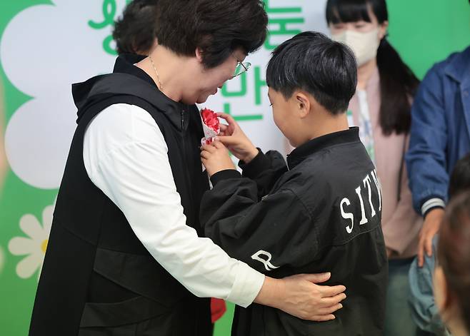 A child pins a carnation corsage onto the clothing of a family member who donated organs, during a Korean Organ Donor Program event in Seodaemun District, western Seoul, on May 1.[YONHAP]