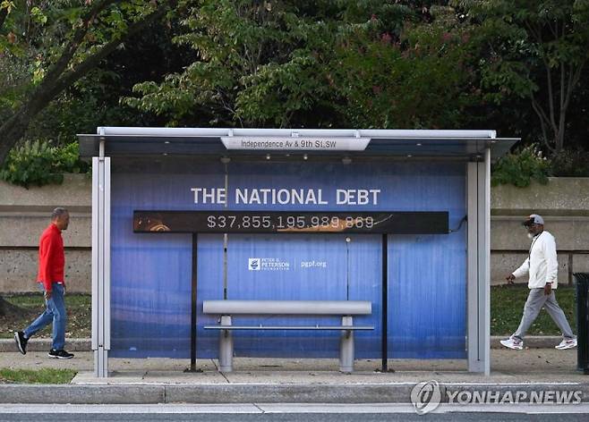 지난 7일(현지시간) 미국 국가 부채 규모 알림판이 부착된 미국 워싱턴 DC 버스 정류장 주변을 지나는 미국인들의 모습. 사진=연합뉴스