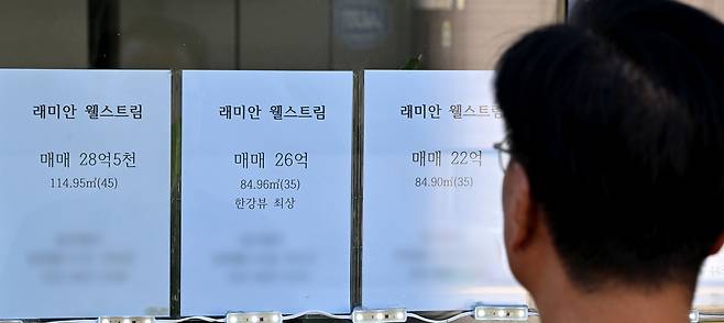 통화당국이 3연속 기준금리 인하를 결정한 배경으로는 꺾이지 않는 서울 집값 상승세와 급격하게 높아진 환율이 있는 것으로 풀이됐다. 사진은 서울 도심 내 한 부동산에 아파트 가격표를 바라 보는 시민 [헤럴드DB]