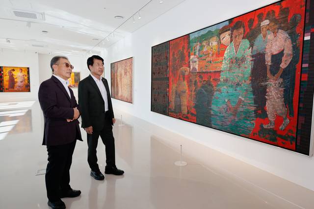 김형성(오른쪽) 한올재단 이사장이 23일 더갤러리호수에서 서강석 송파구청장에게  김흥수 화백의 ‘전쟁과 평화’에 대해 설명하고 있다.  송파구청 제공