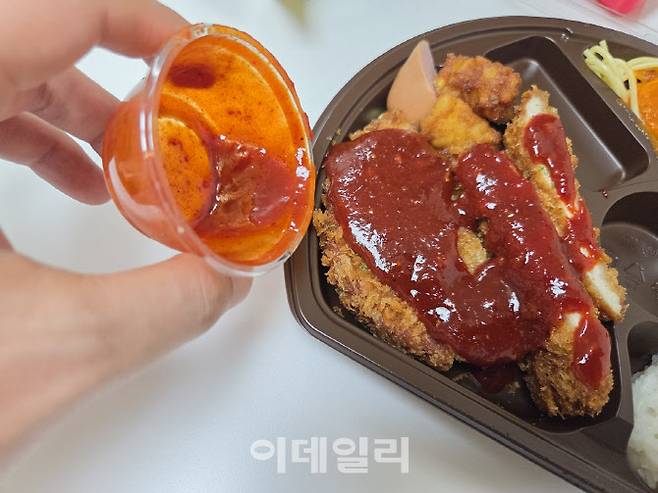 도시락에 별도 제공되는 ‘디진다맛’ 소스를 부은 모습. 검붉고 점성이 짙은 소스가 매운맛의 핵심이다. (사진=한전진 기자)