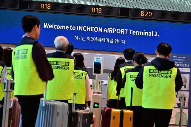 인천국제공항 제2여객터미널 확장 지역에서 실시된 4단계 시설 개장 준비상황 점검 훈련에 참가한 가상 여객들이 셀프 체크인 시스템을 통해 항공권을 발급하고 있다. 뉴시스