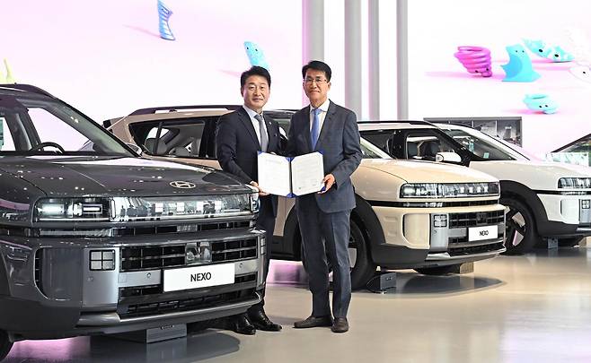 Kim Dong-wook, Executive Vice President of Hyundai Motor Group (right), and Lee Ho-hyun, Second Vice Minister of Trade, Industry and Energy (left), pose for a commemorative photo in front of The All-New NEXO at Hyundai Motorstudio Goyang in July. Photo provided by Hyundai Motor Group