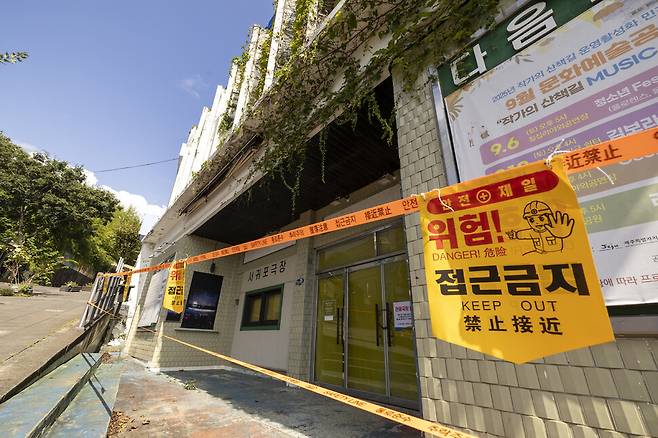 철거 공사가 일시 멈춘 극장을 둘러싸고 가림막과 접근금지 표지판이 시민들의 접근을 막고 있다.