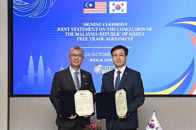 여한구 산업통상부 통상교섭본부장이 지난 26일 말레이시아 쿠알라룸푸르 국제컨벤션센터(KLCC)에서 틍쿠 자프룰 아지즈 말레이시아 투자통상산업부 장관과 한-말레이시아 FTA 타결 공동선언문에 서명한 뒤 기념 촬영하고 있다. 연합뉴스