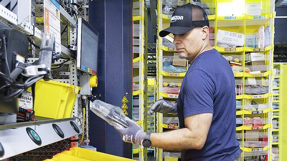 미국 매사추세츠주 찰튼에 위치한 아마존 물류 센터에 아마존 직원이 온라인 주문처리를 위해 상품 보관대에서 물품을 분류하고 있다. EPA=연합뉴스