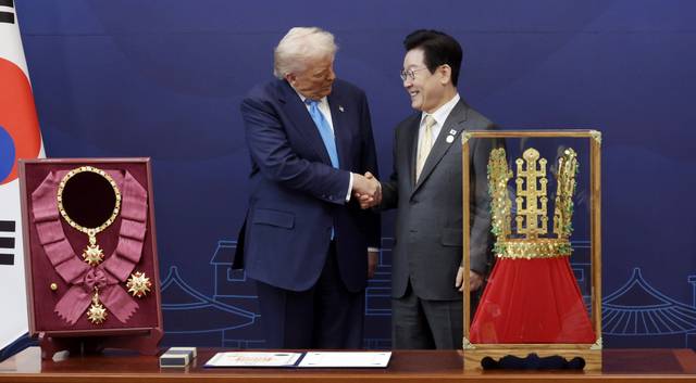 이재명 대통령이 29일 경북 국립경주박물관에서 도널드 트럼프 미국 대통령에게 ‘천마총 금관 모형’을 선물한 뒤 악수하고 있다. 왼쪽은 이 대통령이 트럼프 대통령에게 수여한 무궁화 대훈장.<대통령실통신사진기자단·연합뉴스>