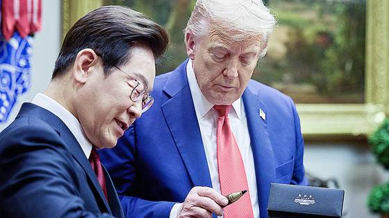 President Lee Jae Myung presents U.S. President Donald Trump with the fountain pen he used to sign the guest book during their Korea-U.S. summit at the White House in Washington on Aug. 25. [YONHAP]