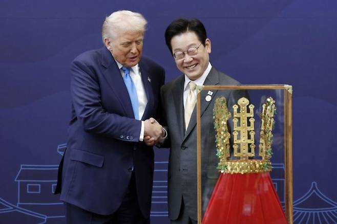 President Lee Jae Myung (right) shakes hands with US President Donald Trump after presenting him with a replica of the Cheonmachong gold crown at the Gyeongju National Museum in North Gyeongsang Province on Wednesday. (Yonhap)