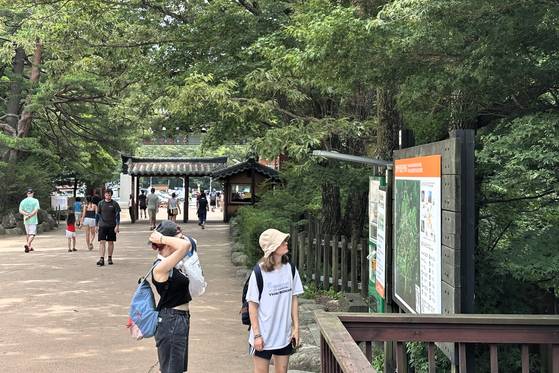 Foreign visitors look at an information sign in Seoraksan National Park. [CHON KWON-PIL]