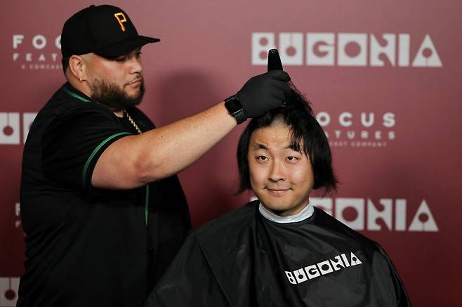 지난 20일(현지시간) 미국 로스앤젤레스에서 진행된 영화 ‘부고니아’ 특별 시사회 현장에서 한 관객이 삭발을 하고 있다. [로이터]