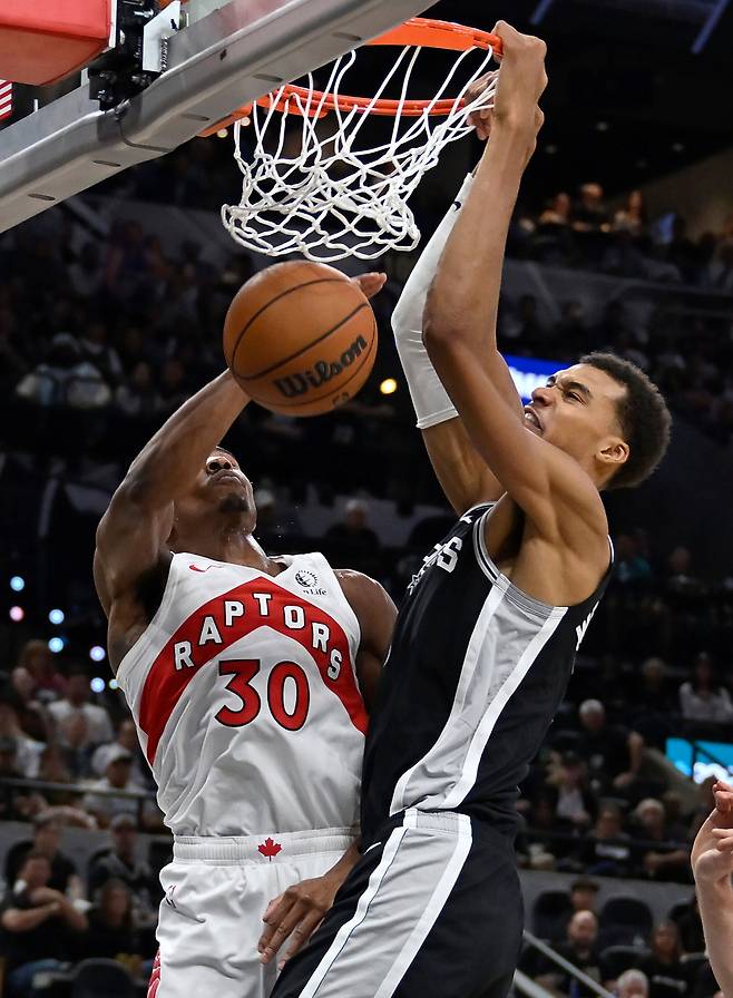 미국 프로농구(NBA) 샌안토니오 스퍼스의 빅터 웸반야마(오른쪽)가 지난 28일(한국시간) 미국 텍사스주 샌안토니오의 프로스트 뱅크 센터에서 열린 토론토 랩터스와의 맞대결에서 오차이 아바지의 수비를 뚫고 투핸드 덩크를 꽂아넣고 있다. 샌안토니오=AP연합뉴스