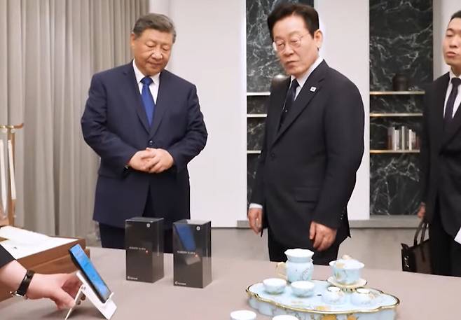 1일 경주 아시아태평양 경제협력체(APEC) 정상회의를 계기로 열린 한중 정상회담에서 이재명 대통령이 시진핑 중국 국가주석이 준비한 샤오미 스마트폰 등 선물을 둘러보고 있다. 유튜브 화면 갈무리
