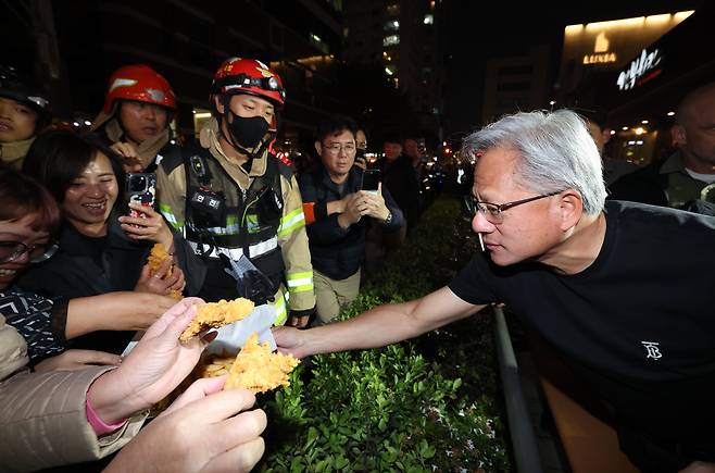 젠슨 황 엔비디아 최고경영자가 30일 서울 삼성동 한 치킨집에서 진행된 이재용 삼성전자 회장, 정의선 현대차그룹 회장과 치맥 회동 중 시민에게 치킨과 감자튀김을 나눠주고 있다. 김경록 기자
