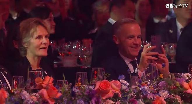 마크 카니(왼쪽) 캐나다 총리가 지난 31일 경북 경주 라한셀렉트호텔 대연회장에서 열린 '2025 아시아태평양경제협력체(APEC) 정상회의' 환영 만찬 공연 무대에 오른 가수 지드래곤을 휴대폰으로 촬영하고 있다. 연합