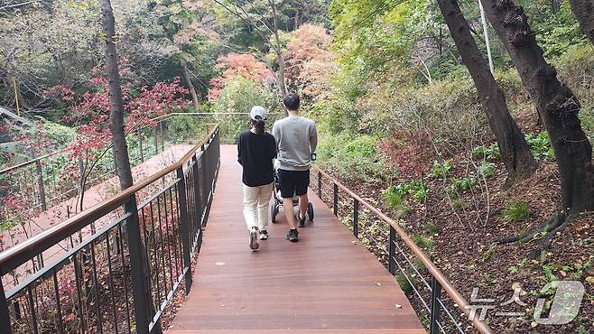 유모차를 밀며 완만한 데크길을 걷는 부부의 모습. '남산 하늘숲길'은 경사 8% 이내의 무장애 산책로다. 2025.10.31/뉴스1 ⓒ News1 한지명 기자