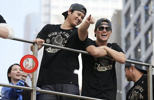 3일(현지 시간) 미국 캘리포니아주 로스앤젤레스에서 열린 LA 다저스 메이저리그 월드시리즈 2연패 달성 기념 카퍼레이드에서 오타니 쇼헤이(왼쪽)와 야마모토 요시노부가 팬들을 바라보고 있다. 오타니의 아내인 다나카 마미코가 아이폰 13 미니로 오타니를 찍고 있다. /사진=뉴시스