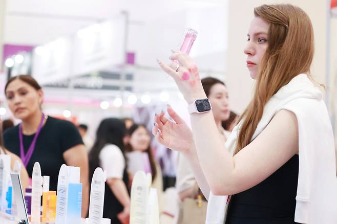 An attendee examines products at the 2025 Seoul International Cosmetics & Beauty Industry Expo and International Health Industry Expo at Coex in Gangnam District, southern Seoul, in May. [YONHAP]