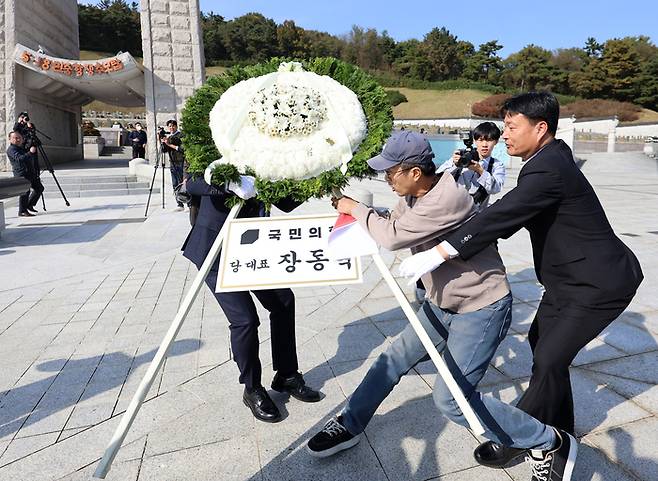 6일 오후 광주 북구 국립 5·18민주묘지에서 장동혁 국민의힘 대표의 참배 화환을 시민단체 관계자가 강제로 이동시키고 있다. [사진 출처 = 연합뉴스]