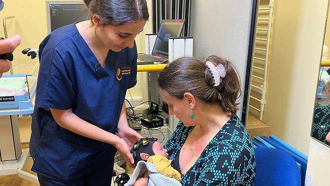 플로라 포르 박사가 아기 테오와 엄마 스타니 게오르기예바와 함께 실험을 진행 중이다