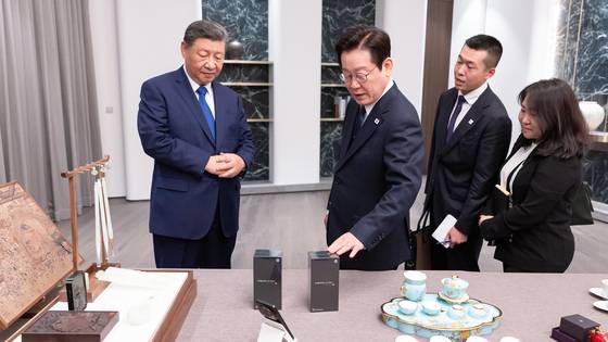 이재명 대통령이 시진핑 중국 국가주석에게 받은 샤오미 스마트폰을 살펴보고 있다. 연합뉴스