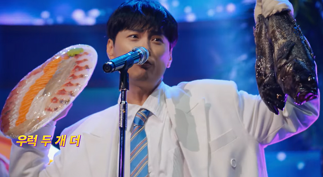 가수 민경훈이 회 한 접시와 우럭 2마리를 들고 노래 <나에게로 떠나는 여행>에서 “활어회~ 물회 원샷~ 우럭 두개 더~”를 부르고 있는 지마켓 ‘빅스마일 데이’ 광고의 한 장면. 광고 영상 캡쳐