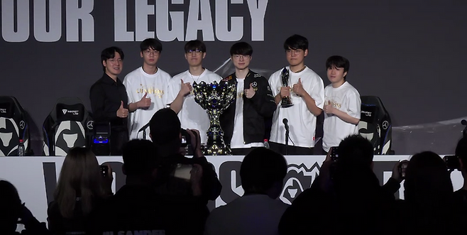 T1 선수단이 9일 중국 청두에서 열린 2025 리그 오브 레전드 월드 챔피언십(롤드컵) 결승전에서 우승한 후 소환사의 컵을 앞에 두고 기념촬영을 하고 있다. 온라인 기자회견 캡처.
