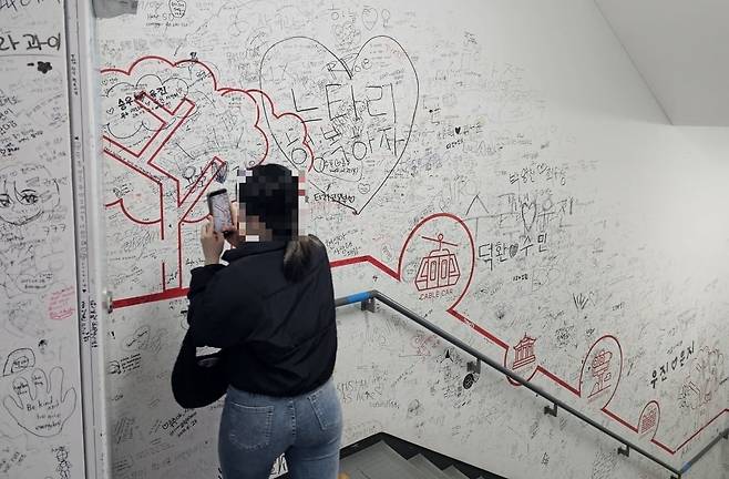 지난 8일 한 외국인 관광객이 남산 서울타워 내부 벽면에 낙서를 한 뒤 기념사진을 찍고 있다. 권용훈 기자