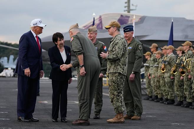 다카이치 사나에(왼쪽에서 둘째) 일본 총리가 지난달 28일 가나가와현 요코스카 미군 기지에 정박 중인 미 항공모함 조지워싱턴함 갑판에 올라 군 관계자와 악수하는 장면을 도널드 트럼프 미국 대통령이 지켜보고 있다. 다카이치는 이날 “평화는 말이 아닌, 확고한 결의와 행동에 의해서만 지켜진다”고 했다./AP 연합뉴스