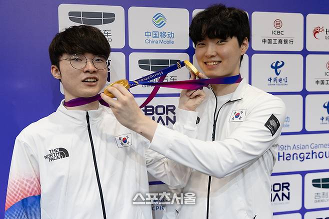 ‘페이커’ 이상혁(왼쪽)과 ‘쵸비’ 정지훈이 서로의 금메달을 잡고 장난을 치고 있다. 사진 | 공동취재단