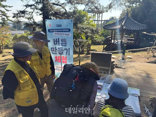 6일 제주시 저지오름에서 느영나영복지공동체 어르신들이 환경보전 인식 캠페인 부스에서 방문객들과 ‘버튼 만들기 체험’을 진행하고 있다. ⓒ한국노인인려개발원
