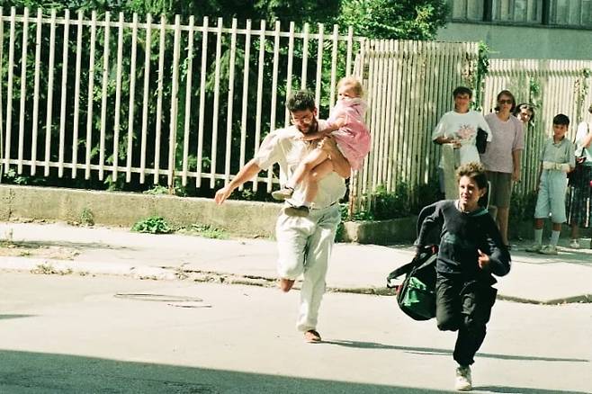 저격수들의 총알이 언제 쏟아질지 모르는 사라예보 거리에서 한 아버지가 딸을 안고 급히 거리를 가로질러 뛰고 있다./자료 사진