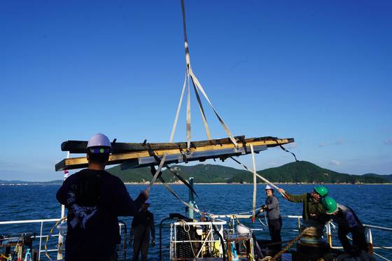 Wreckage from Mado wreck No. 4, the only existing ship from the Joseon Era (1392-1910), is being hoisted from the coast of Mado Island, near South Chungcheong's Taean, in October this year by the National Research Institute of Maritime Culture Heritage under the Korea Heritage Service. [KOREA HERITAGE SERVICE]