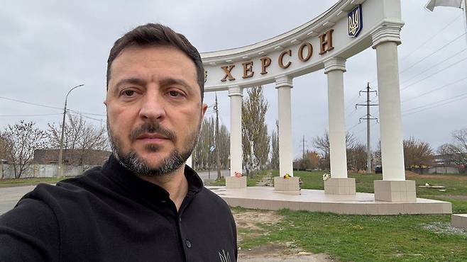 [헤르손=AP/뉴시스] 볼로디미르 젤렌스키 우크라이나 대통령이 11일(현지 시간) 우크라이나 남부 최전선 도시 헤르손을 방문해 '헤르손'이라고 적힌 진입로에서 셀카를 찍고 있다. 2025.11.12.