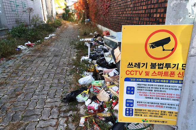 쓰레기 불법투기 신고 안내판 아래 쓰레기  (대구=연합뉴스) 박세진 기자 = 지난 14일 대구 동구 효목2동 화랑로 17·19길 민영 개발 구역 일대에 빈집과 쓰레기가 방치돼 있다. 2025.11.14 psjpsj@yna.co.kr