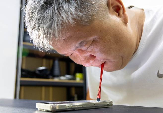 중증화상 산재로 양팔을 절단한 이주노동자 오기나가 입으로 휴대전화 문자를 보내고 있다. 김진수 선임기자 jsk@hani.co.kr