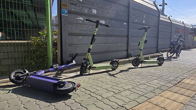 Electric scooters are left abandoned on a sidewalk near Dujeong Station in Seobuk District, Cheonan, South Chungcheong, on the morning of Nov. 11. [SHIN JIN-HO]
